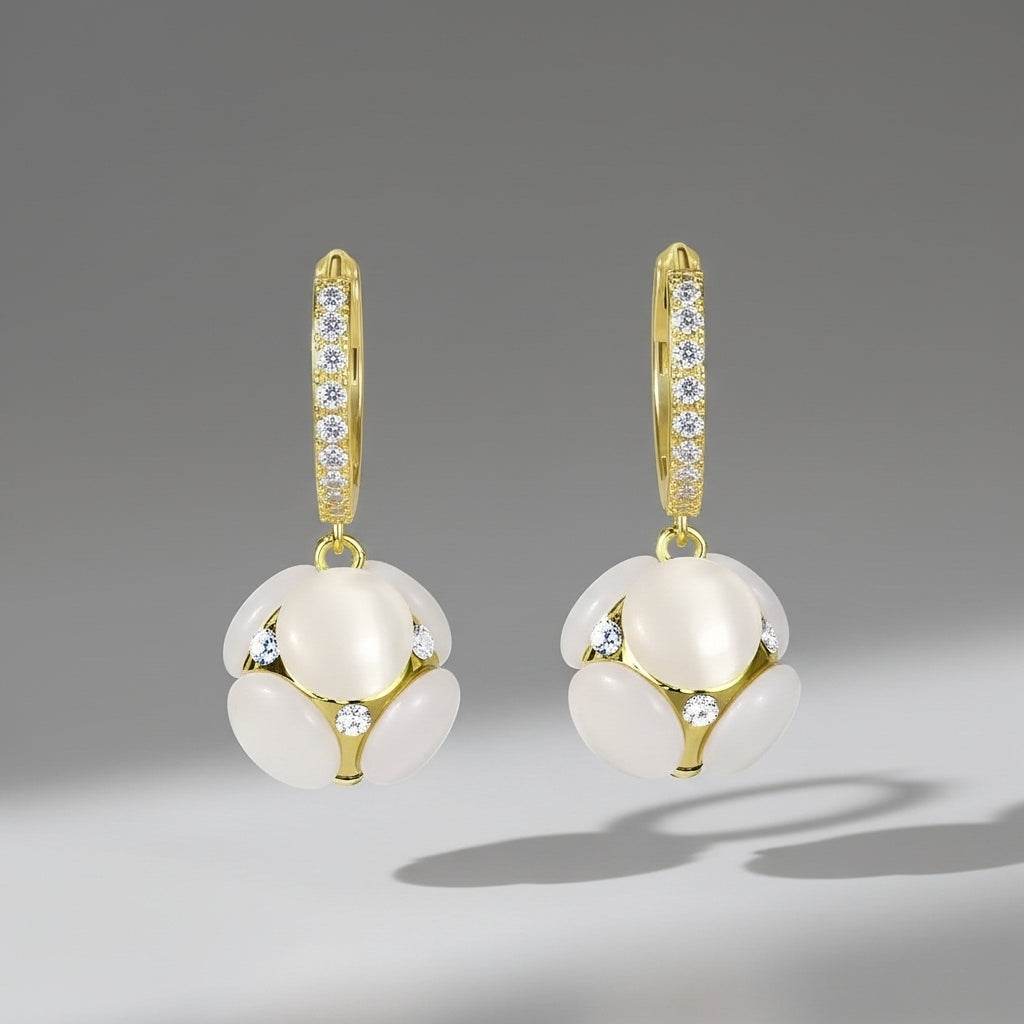 Gold earrings with white spherical stones on a gray background
