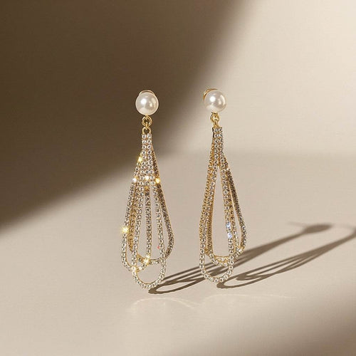 Pair of gold and pearl earrings on a beige background