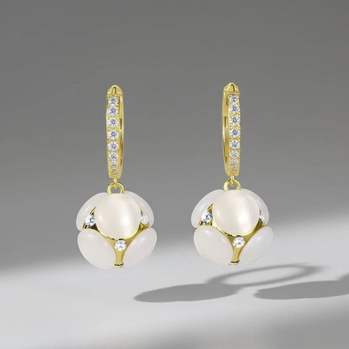 Gold earrings with white spherical stones on a gray background