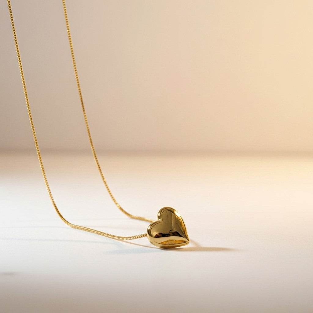 Gold heart-shaped pendant on a chain against a beige background