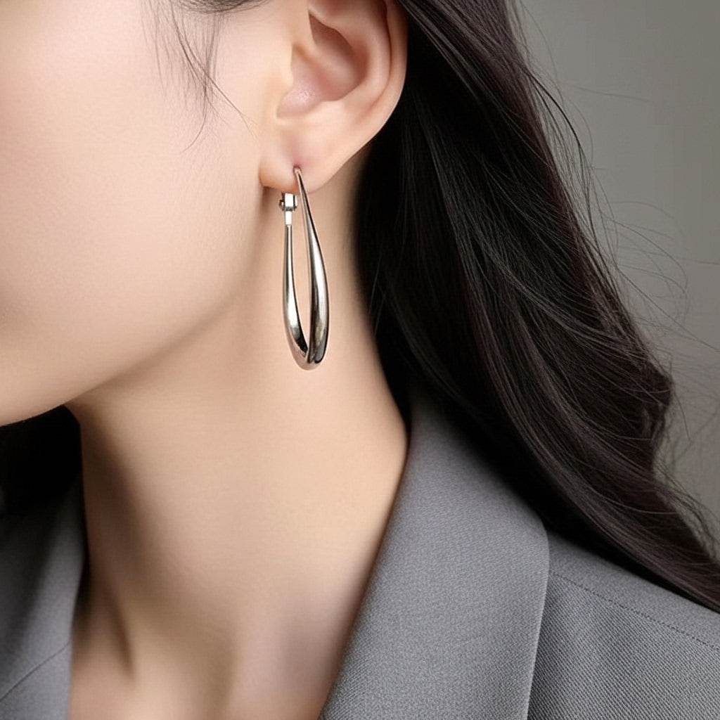 Silver hoop earring worn by a person with a neutral background