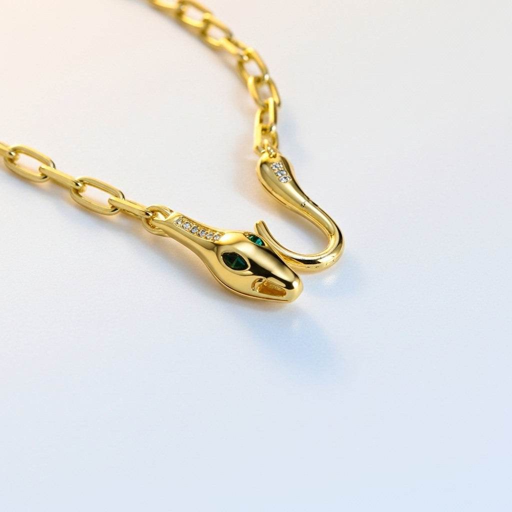 Gold snake-shaped bracelet with green eyes on a light background