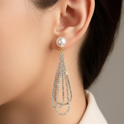 Pearl earring with dangling crystal strands worn by a person