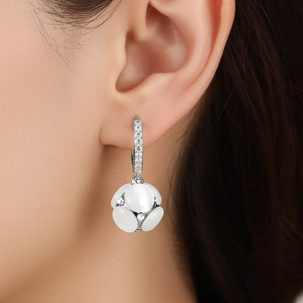 Close-up of a silver earring with a white gemstone worn by a person.