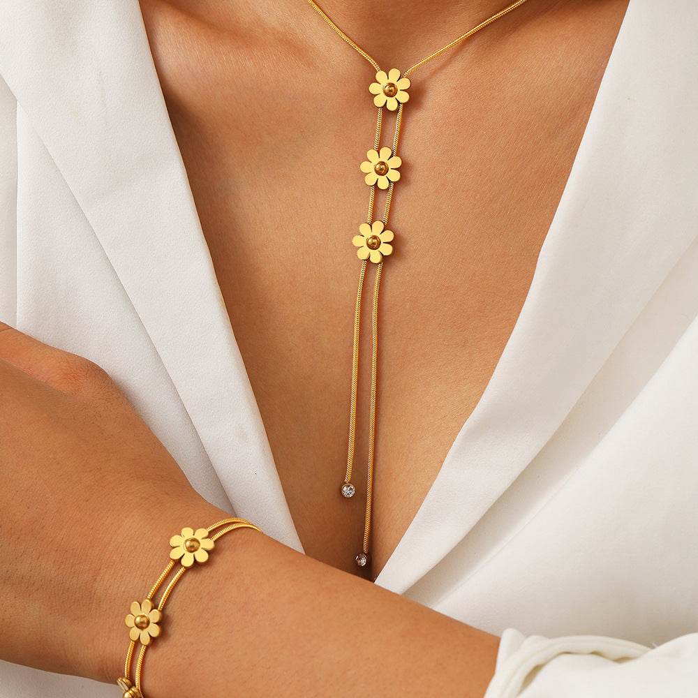 Gold floral necklace and bracelet on a person wearing a white top.