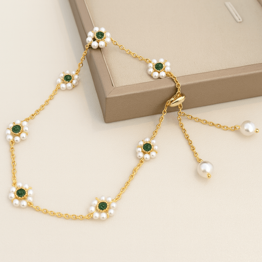Gold necklace with emeralds and pearls on a beige surface